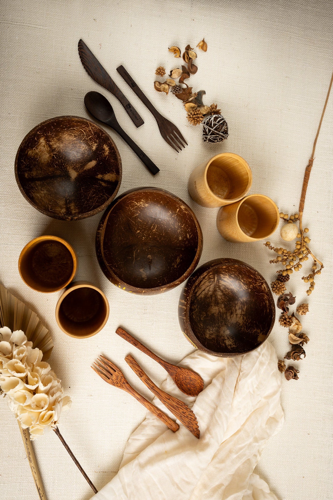 Set of wooden bowls, spoons, and forks on a textured surface with decorative elements.